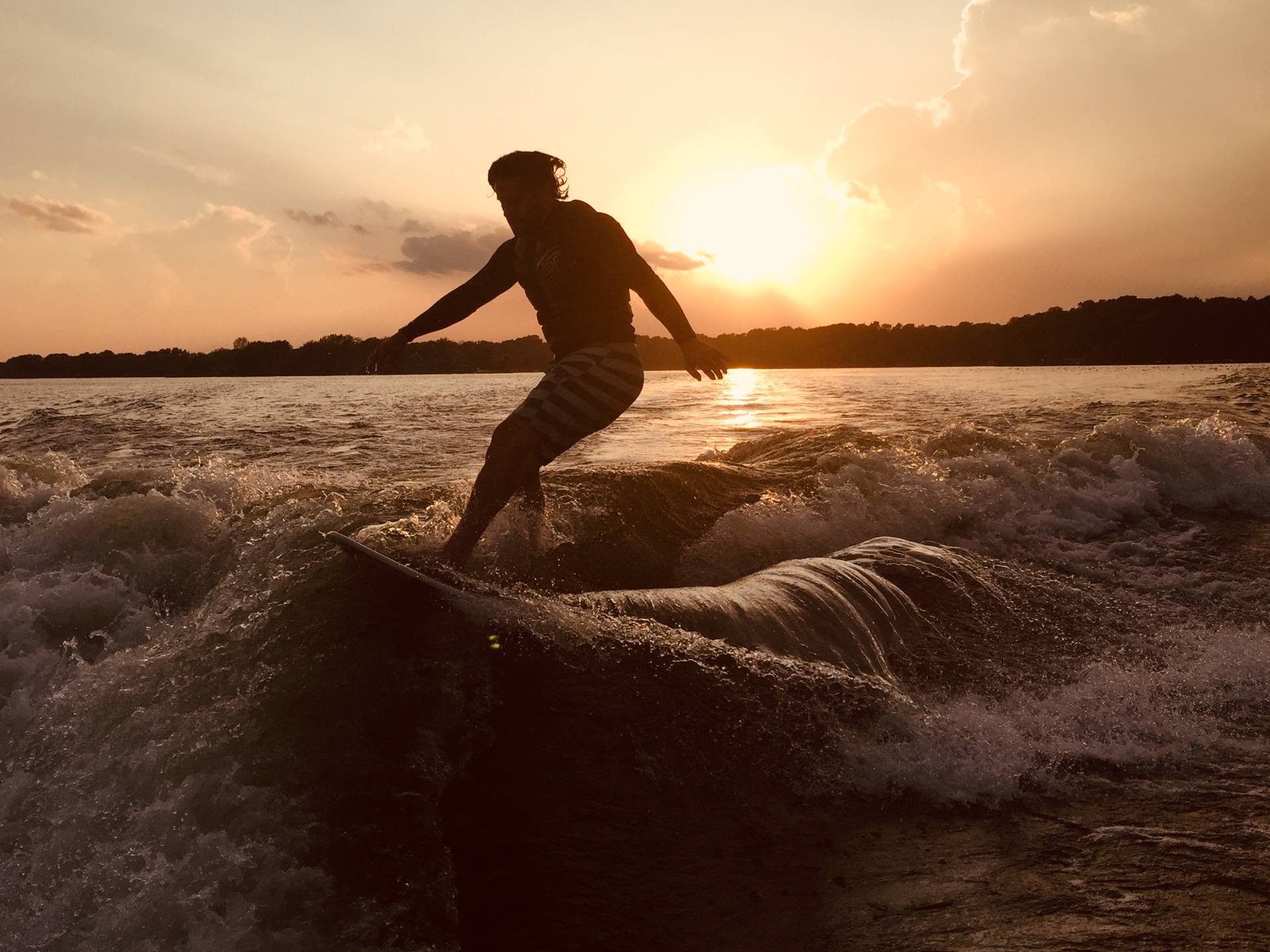 Sunlit pontoon boat gliding across a calm blue lake at golden hour